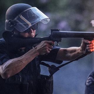 En polis avfyrar en gummikula.