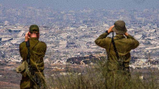 Israelisk militär blickar över ett sönderbombat Gaza. Enligt uppgifter försöker Egypten och Qatar få till en vapenvila mellan Israel och Hamas.
