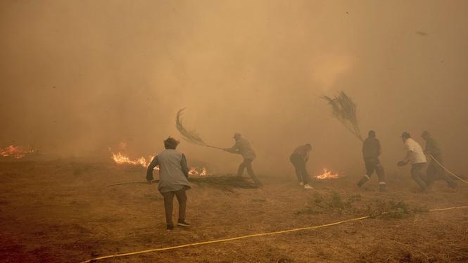 Invånare försöker släcka en brand som rasar i byn Rebordondo i nordvästra Spanien under måndagen.