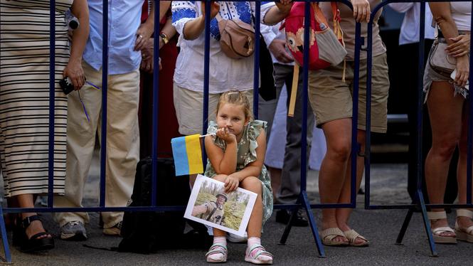 A child holds a photograph of a Ukrainian serviceman during an event of solidarity with Ukraine, marking its upcoming Aug. 24 Independence Day, in Bucharest, Romania, Thursday, Aug. 21, 2025. (AP Photo/Andreea Alexandru)  XVG104