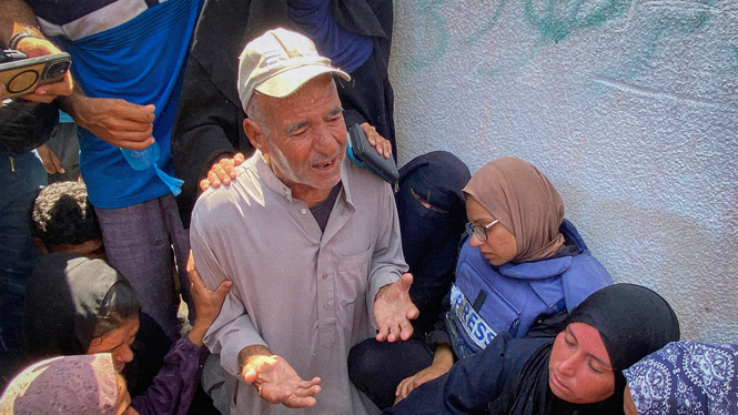 Riyad Dagga ber över sin dotters, frilansjournalisten Mariam Dagga, kropp under hennes begravning efter att hon dödats i den israeliska attacken mot Nasser-sjukhuset i Khan Younis, södra Gazaremsan. Runtom sörjer släktingar och vänner.