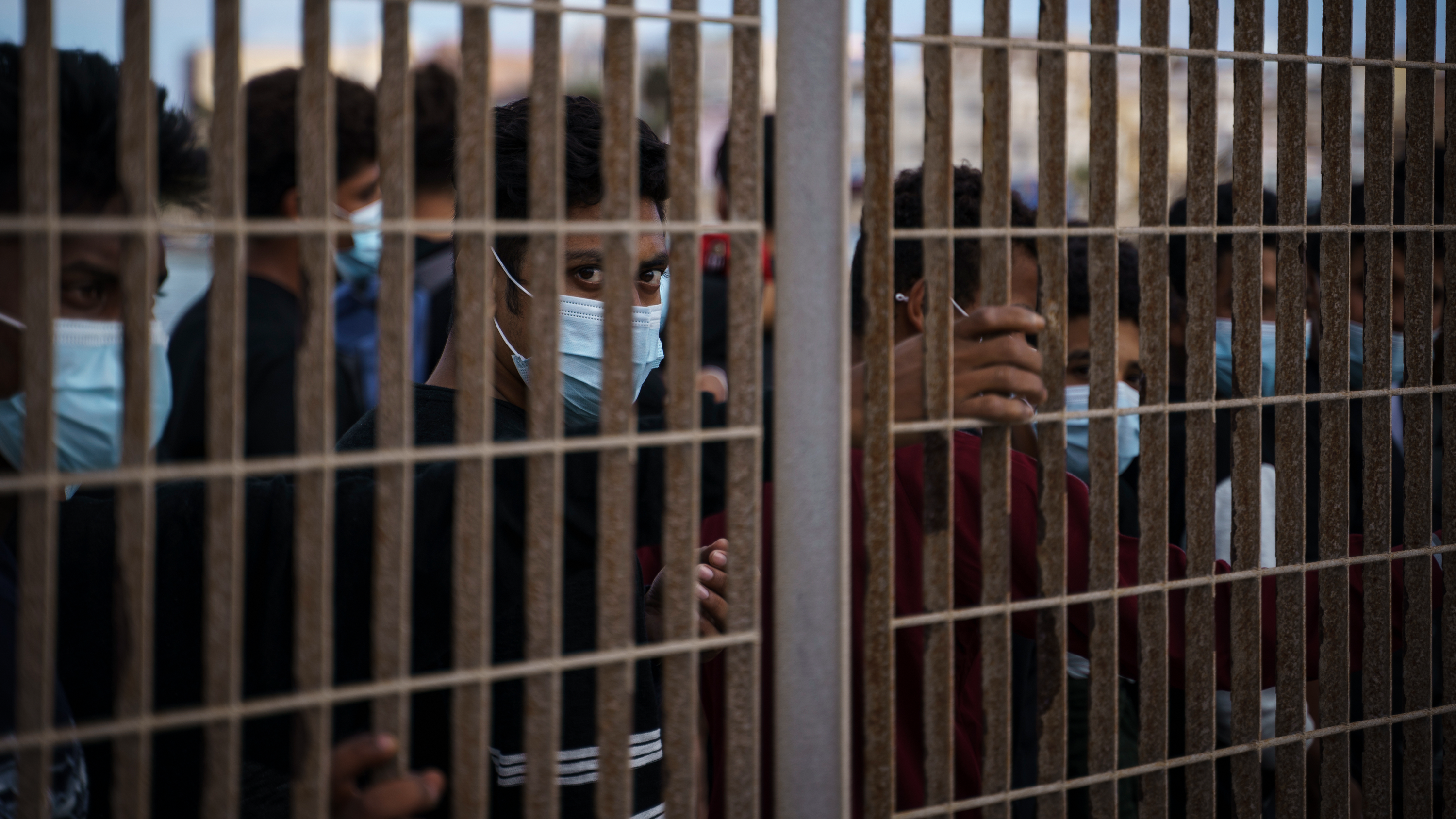 Migranter som korsat Medelhavet med båt köar bakom ett staket i Lampedusa, Italien, fredagen den 1 oktober 2021, medan de väntar på att gå ombord på en färja till Sicilien. 