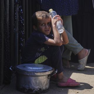 En palestinsk pojke sitter på marken utanför ett matutdelningskök i Khan Younis, södra Gazaremsan.