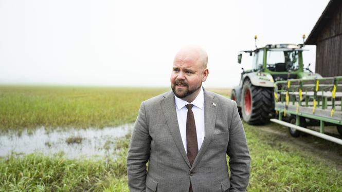 Landsbygdsminister Peter Kullgren framför översvämmad åkermark.