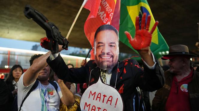 Döda! Döda! Så står det i pratbubblan som demonstranten, maskerad till Rio de Janeiros guvernör Claudio Castro, bär runt sin hals.