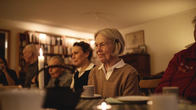 Fikavärden Kerstin får slå sig ner efter att ha serverat fika till alla gäster. Intill henne sitter chauffören Linda.