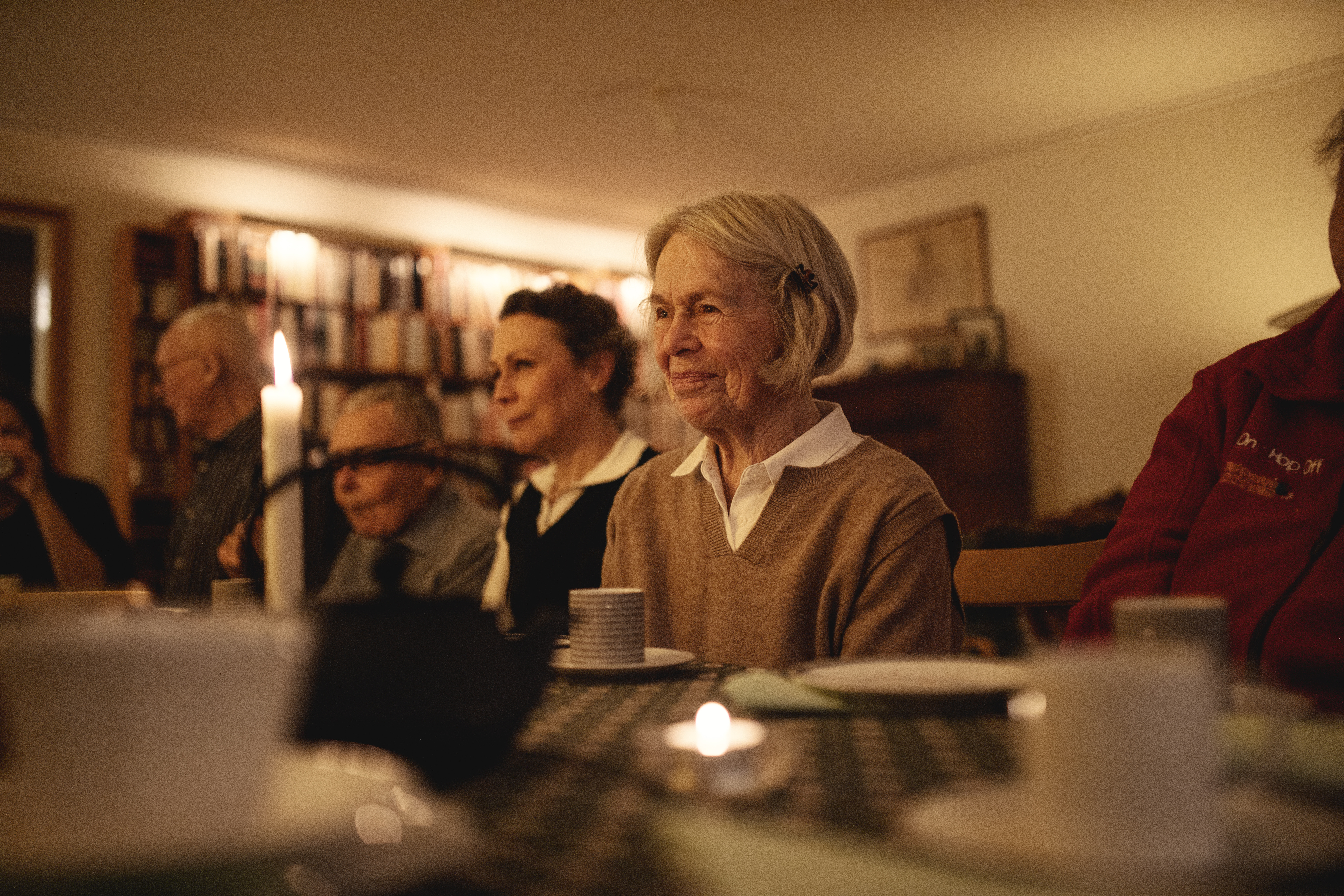 Fikavärden Kerstin får slå sig ner efter att ha serverat fika till alla gäster. Intill henne sitter chauffören Linda.