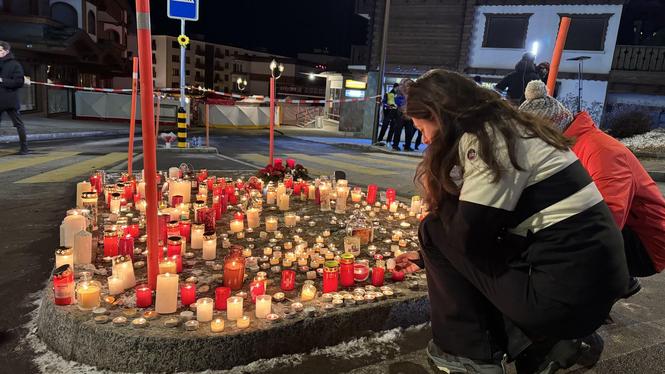 Människor tänder ljus vid en minnesplats nära baren Le Constellation i Crans-Montana, Schweiz, där minst ett 40-tal människor omkom vid en brand på nyårsnatten.