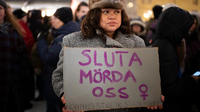 Det är en kall januarifredag. En deltagare håller upp ett plakat på en manifestation mot mäns våld mot kvinnor.