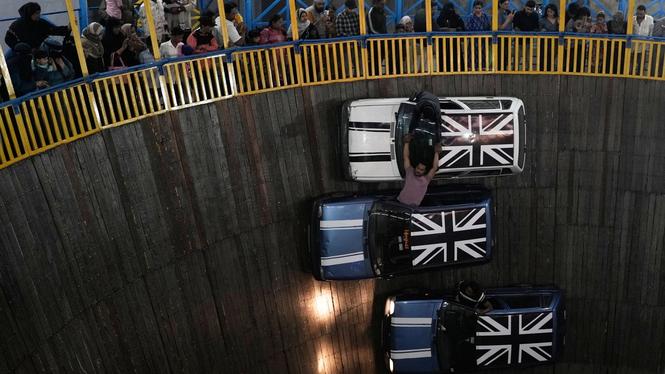 Besökare ser på när stuntmän kör sina bilar i en inhägnad som kallas Maut ka Kuan, eller dödens brunn, i Hyderabad, Indien.