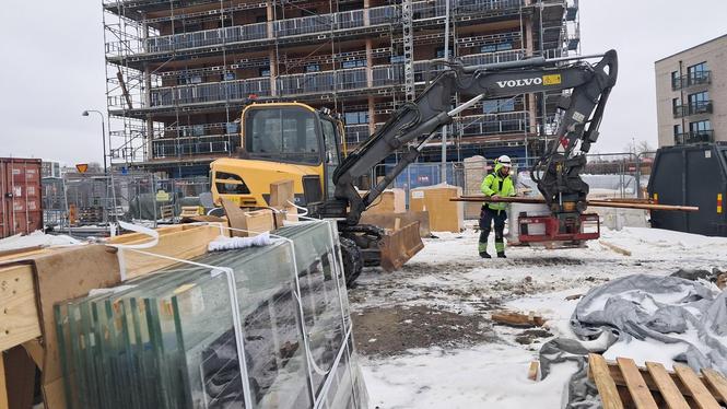 Här lastas trätrall till balkonger på husets översta våningsplan. I förgrunden syns solceller som installeras i balkongbalustraderna.