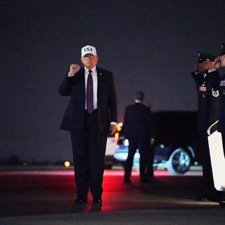 USA:s president Donald Trump höjer näven i luften efter att ha landat i Florida på fredagskvällen.