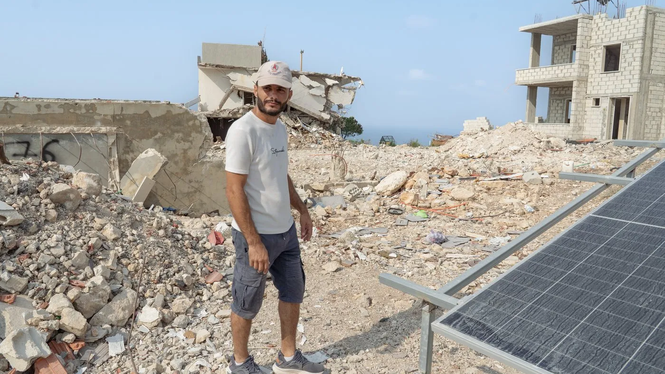 Hassan Awdi visar upp resterna av sitt förra hus, som bombades sönder av Israel hösten 2024. 
