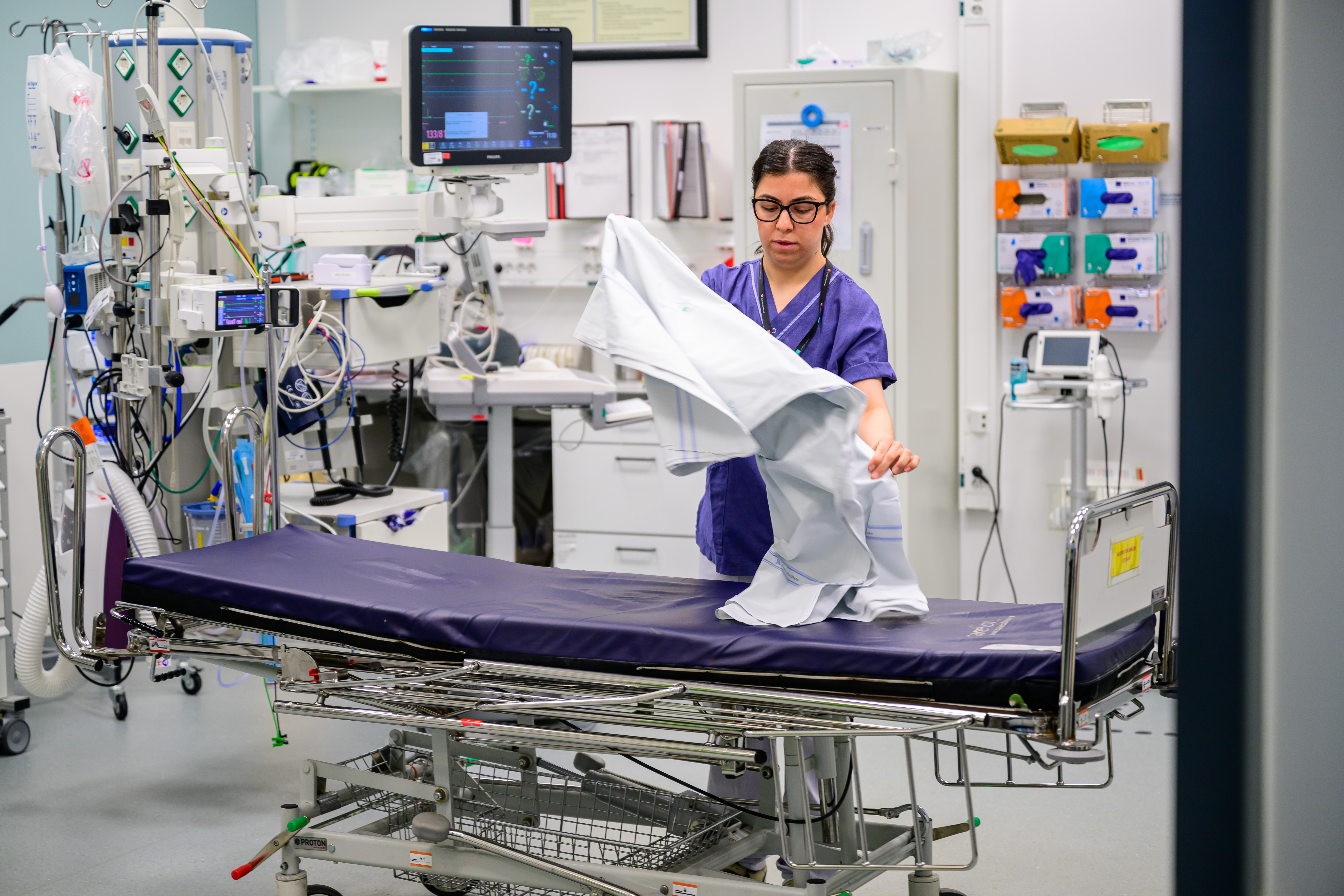 Sköterska bäddar brits i akutrum på sjukhus.