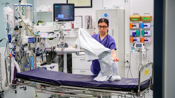 Sköterska bäddar brits i akutrum på sjukhus.