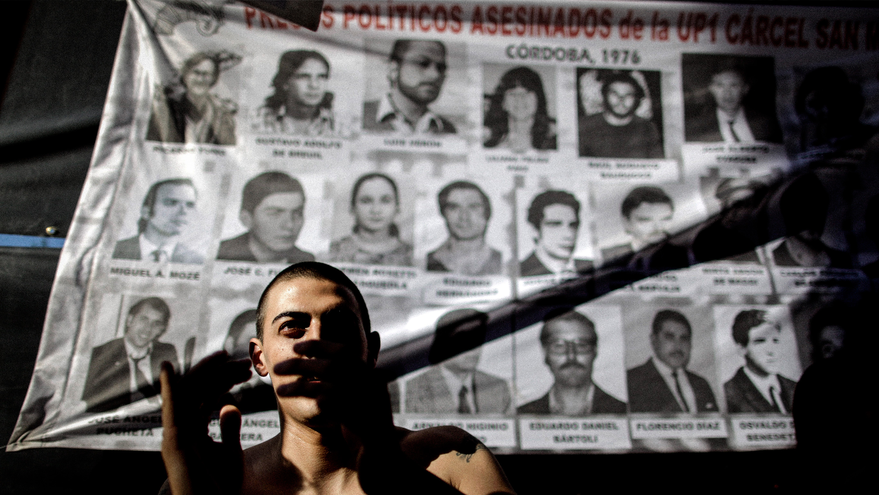 En man applåderar framför bilder av militärdiktaturens offer efter att juntans första ledare, Jorge Rafael Videla, fällts i domstol för tortyr och mordet på 31 stycken fängslade 1976.