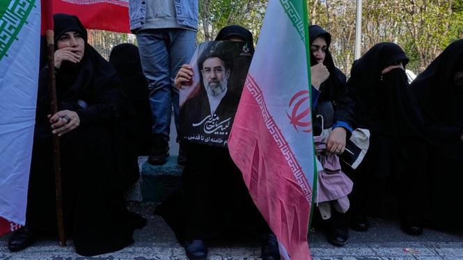 Människor håller den Iranska flaggan och en bild på Irans döde ledare ayatollah Mojtaba Khamenei i Teheran.