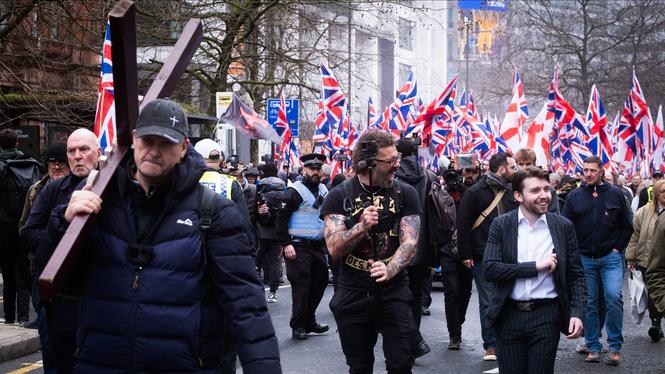 Brittiska och engelska flaggor ackompanjeras av ett träkors när det högerextrema partiet Britain First tågar genom Manchester.