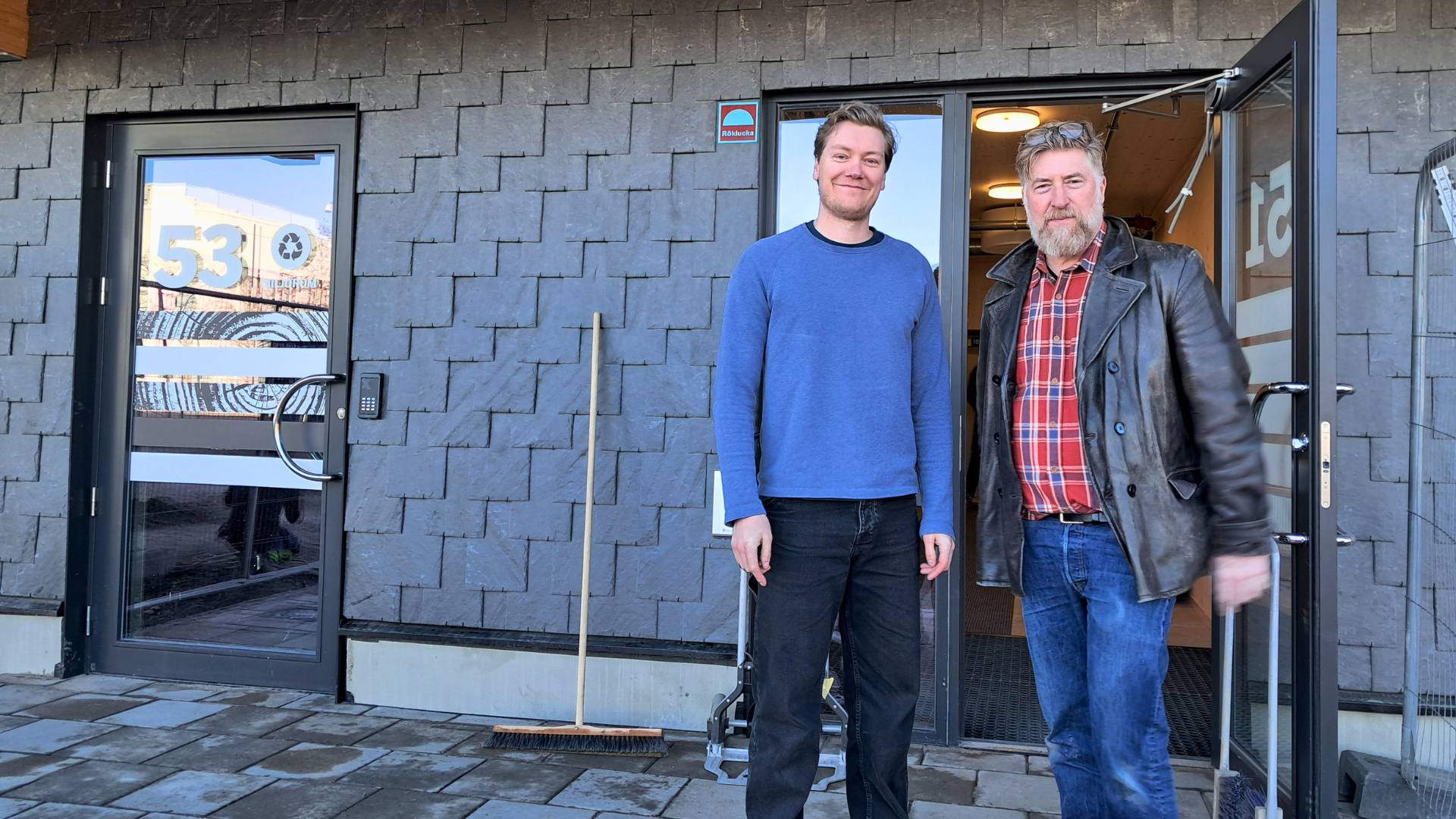 Martin Palm och Fredrik Fagerberg framför huvudentrén. De stor på återbrukade betongplattor och bakom dem syns återbrukat skiffer på fasadens nedre del.