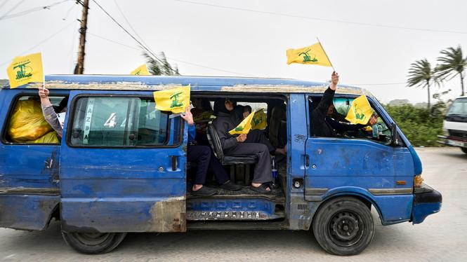 En familj återvänder till sin by i södra Libanon efter att avtalet om vapenvila slutits. De gula flaggorna som det viftas med står för Hizbollah.