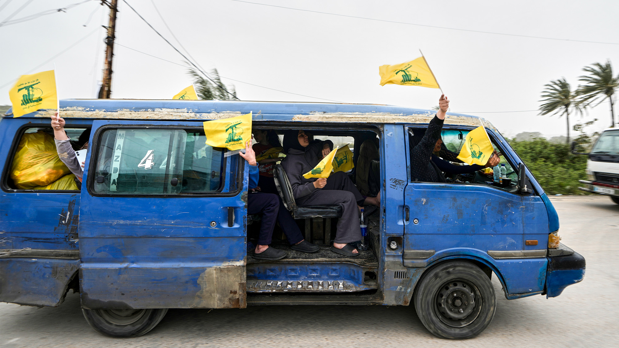 En familj återvänder till sin by i södra Libanon efter att avtalet om vapenvila slutits. De gula flaggorna som det viftas med står för Hizbollah.