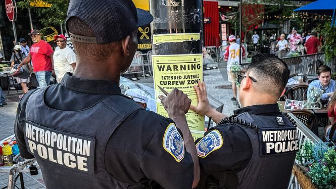 Lokalpolisen sätter upp affischer om utegångsförbudet vid närheten av Nationals park, Washington DC.