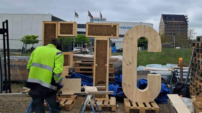 Utanför byggboden: Bokstäverna ETC, tillverkade i trä och halm. Under invigningen av huset kommer de att pryda scenen. I bakgrunden syns det 36 meter höga huset.