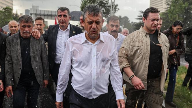 Oppositionsledaren Özgur Özel går mot det turkiska parlamentet i ett regnigt Ankara efter att polisen stormat hans partis högkvarter. 