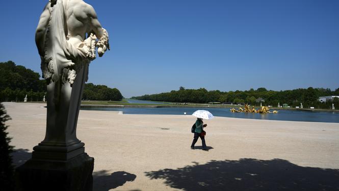 Hettan i frankrike har klättrat allt högre under veckan. Turisterna vid Versailles använder paraplyn för att skydda sig från solen. 